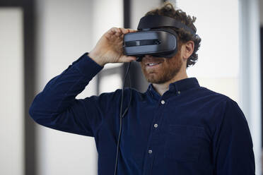 Businessman wearing VR glasses in office - RBF07328