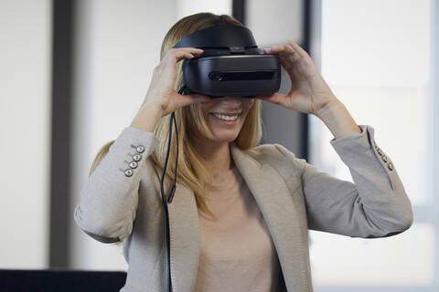 Smiling businesswoman wearing VR glasses in office stock photo