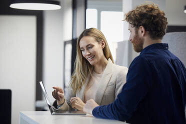 Businessman and businesswoman working together with laptop in office - RBF07333