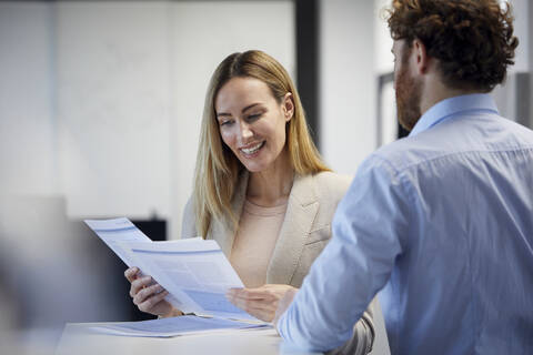 Businessman and businesswoman working together on papers in office stock photo