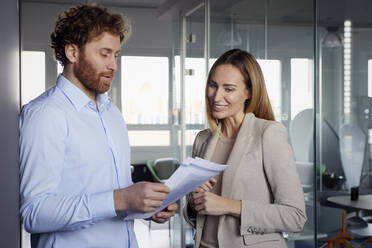 Geschäftsmann und Geschäftsfrau arbeiten gemeinsam an Papieren im Büro - RBF07338