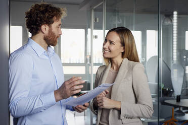 Geschäftsmann und Geschäftsfrau arbeiten gemeinsam an Papieren im Büro - RBF07339