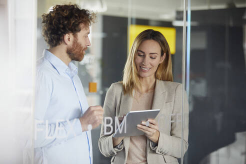 Businessman and businesswoman working together with tablet in office - RBF07346