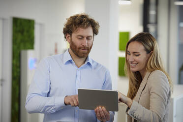 Geschäftsmann und Geschäftsfrau arbeiten zusammen mit Tablet im Büro - RBF07348