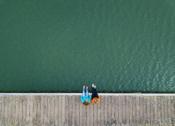 Zwei Freunde sitzen nebeneinander auf einem Steg, Stausee Valdemurio, Asturien, Spanien - DGOF00655