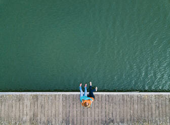 Zwei glückliche Freunde sitzen zusammen auf einem Steg und umarmen sich, Stausee Valdemurio, Asturien, Spanien - DGOF00656