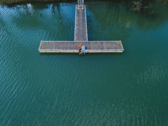 Zwei Freunde sitzen nebeneinander auf einem Steg, Stausee Valdemurio, Asturien, Spanien - DGOF00660