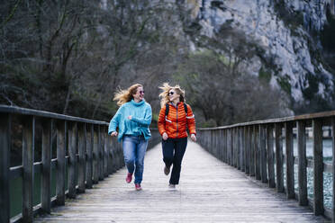 Zwei glückliche Frauen, die gemeinsam auf der Uferpromenade laufen, Stausee Valdemurio, Asturien, Spanien - DGOF00666