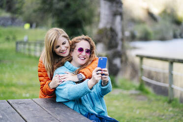 Porträt von zwei glücklichen Freunden, die ein Selfie mit einem Smartphone machen - DGOF00668