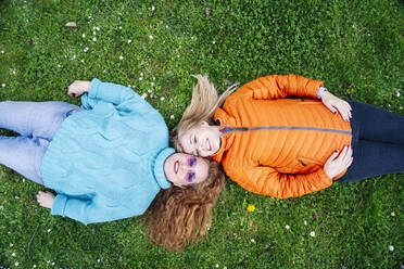 Portrait of two happy friends lying on a meadow - DGOF00669