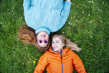 Portrait of two happy friends lying on a meadow - DGOF00670
