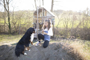 Mädchen spielt im Garten mit ihrem Hund - HMEF00862