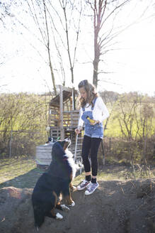 Mädchen spielt im Garten mit ihrem Hund - HMEF00864