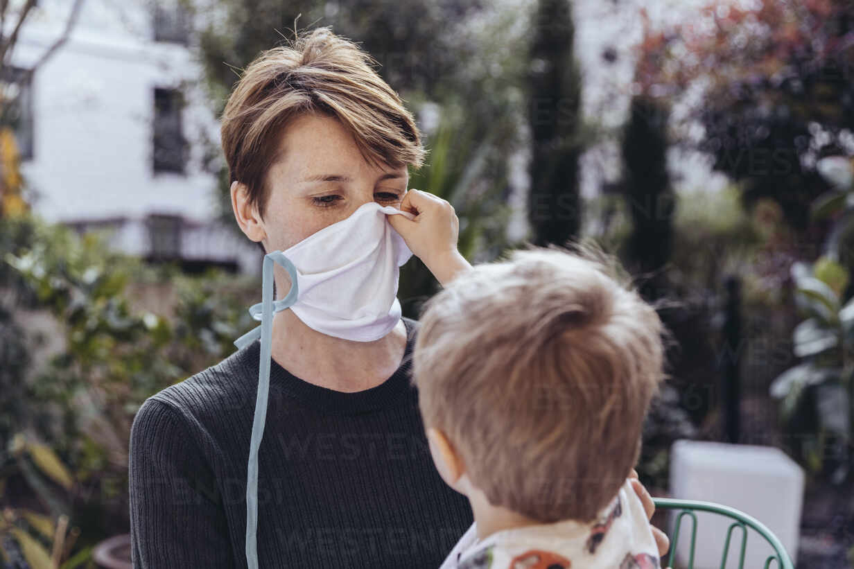 Littley boy helping his mother to put on a face mask stock photo