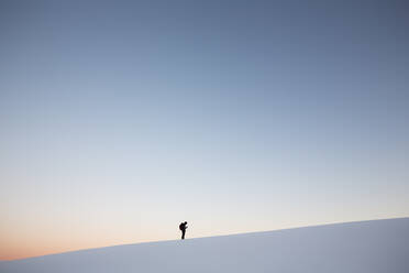 Mann stehend auf schneebedeckten Berg gegen klaren Himmel bei Sonnenuntergang - EYF03426