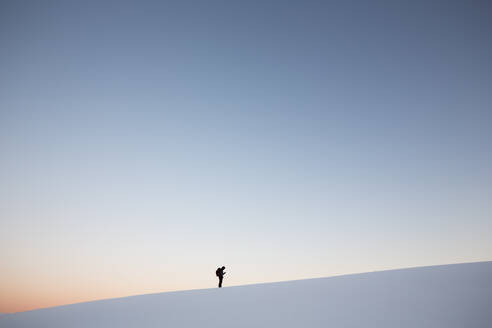 Mann stehend auf schneebedeckten Berg gegen klaren Himmel bei Sonnenuntergang - EYF03426