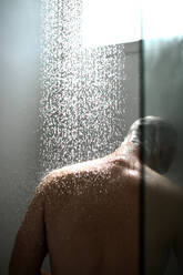 Rückansicht des Mannes unter der Dusche im Badezimmer - EYF03464