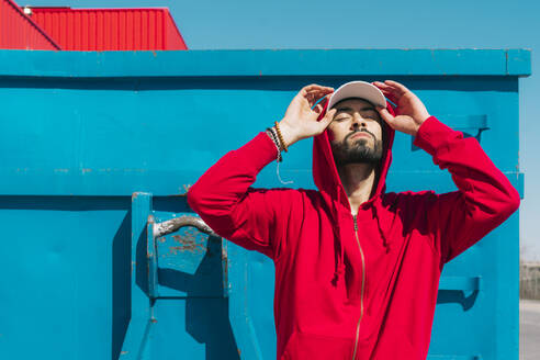 Young man wearing red hoodie, facing the sun - ERRF03116