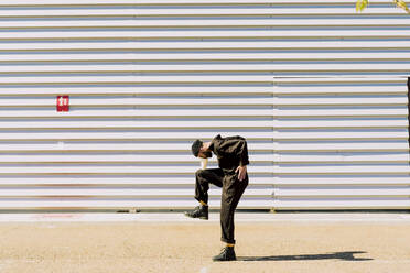Mann in schwarzem Overall balanciert vor einem Industriegebäude - ERRF03166