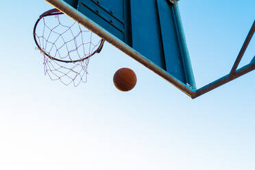 Low Angle View Of Basketball At Hoop Against Clear Sky - EYF03533