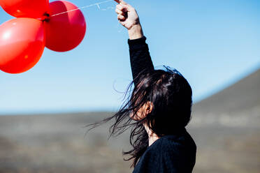 Seitenansicht der jungen Frau hält Ballons am Strand - EYF03543