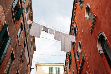 Low Angle View Of Laundry Drying Amidst Buildings Against Sky - EYF03562