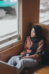 Junge Frau trägt Hijab während sie im Zug sitzt - EYF03613