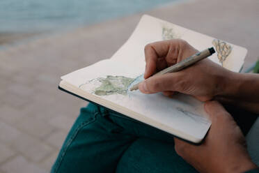 Midsection Of Man Sketching In Book On Footpath - EYF03637