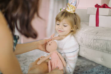 Close-Up Of Mother Giving Toy To Cute Girl At Home - EYF03640