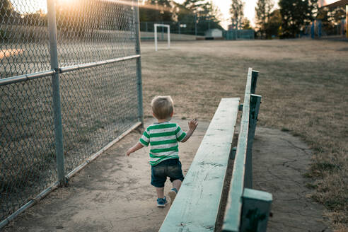Rückansicht des niedlichen Jungen zu Fuß auf Spielfeld bei Sonnenuntergang - EYF03651
