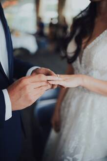Midsection of Man Putting Ring auf Braut Finger während der Hochzeitszeremonie - EYF03701