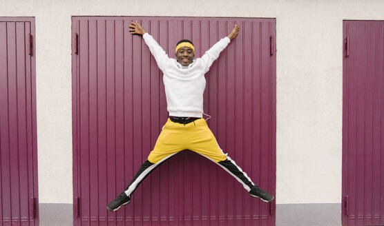 Portrait of smiling young man in sportswear jumping in the air - AHSF02185