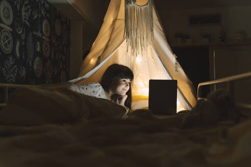 Smiling girl lying on bed using laptop - ERRF03197