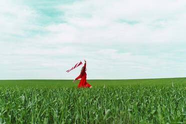 Frau in rotem Kleid läuft auf einem Feld mit Windsack - ERRF03224