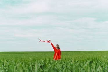 Blond young woman wearing green dress lying on a field with eyes closed  stock photo