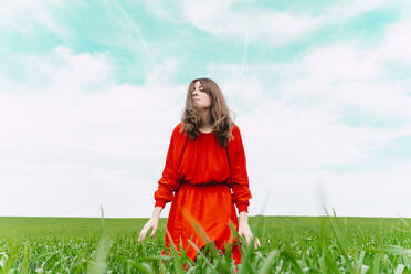 Frau in rotem Kleid entspannt sich auf einem Feld mit geschlossenen Augen - ERRF03231