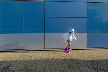 Kleines Mädchen mit Schutzhelm beim Inlineskaten im Sonnenlicht - ERRF03273