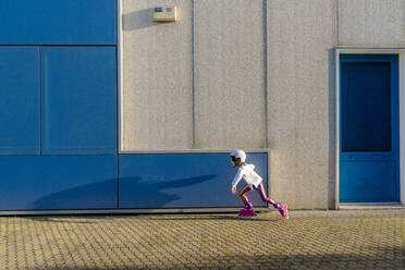 Kleines Mädchen mit Schutzhelm beim Inlineskaten im Sonnenlicht - ERRF03274