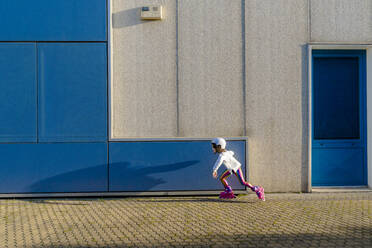 Little girl with safety helmet inline skating at sunlight - ERRF03274