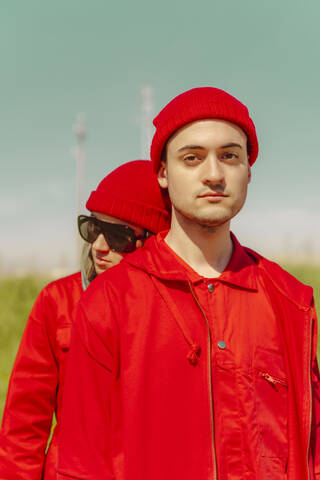 Porträt eines jungen Mannes und seiner Freundin in roter Kleidung im Freien, lizenzfreies Stockfoto