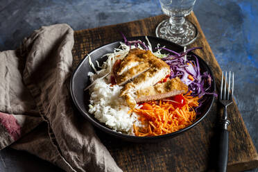 Bowl of ready-to-eat salad with white and red cabbage, carrots, rice and chicken schnitzel - SBDF04238