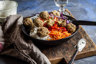 Bowl of ready-to-eat salad with white and red cabbage, carrots, rice and spinach falafel - SBDF04240