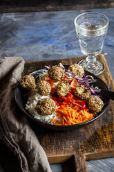 Bowl of ready-to-eat salad with white and red cabbage, carrots, rice and spinach falafel - SBDF04241