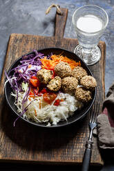 Bowl of ready-to-eat salad with white and red cabbage, carrots, rice and spinach falafel - SBDF04244