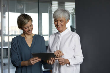 Zwei Geschäftsfrauen teilen sich ein Tablet im Büro - RBF07351