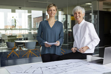 Portrait of two confident businesswomen with construction plan in office - RBF07415
