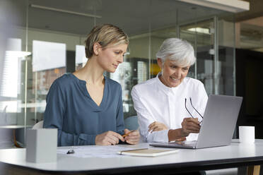 Two businesswomen working together with laptop in office - RBF07417