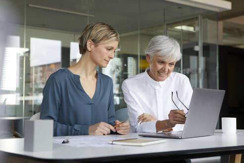 Zwei Geschäftsfrauen arbeiten zusammen mit einem Laptop im Büro - RBF07417