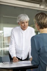 Zwei Geschäftsfrauen im Gespräch am Schreibtisch im Büro - RBF07423