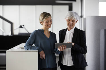 Zwei Geschäftsfrauen teilen sich ein Tablet im Büro - RBF07426